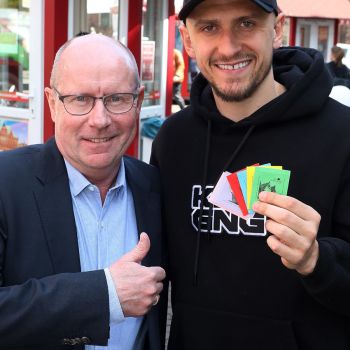 Dietmar Hoppe (eingefleischter Werderaner und Geschäftsführer der Bürgerpark-Tombola) und Miloš Veljković auf dem Liebfrauenkirchhof nach der Ziehung mit den diesjährigen Losen. Foto: Martin Rospek